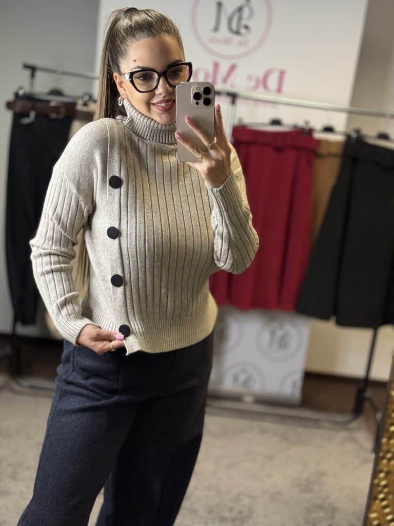 Női modell bézs kötött garbós pulóvert visel, szemből fotózva, tükörben készített selfie.