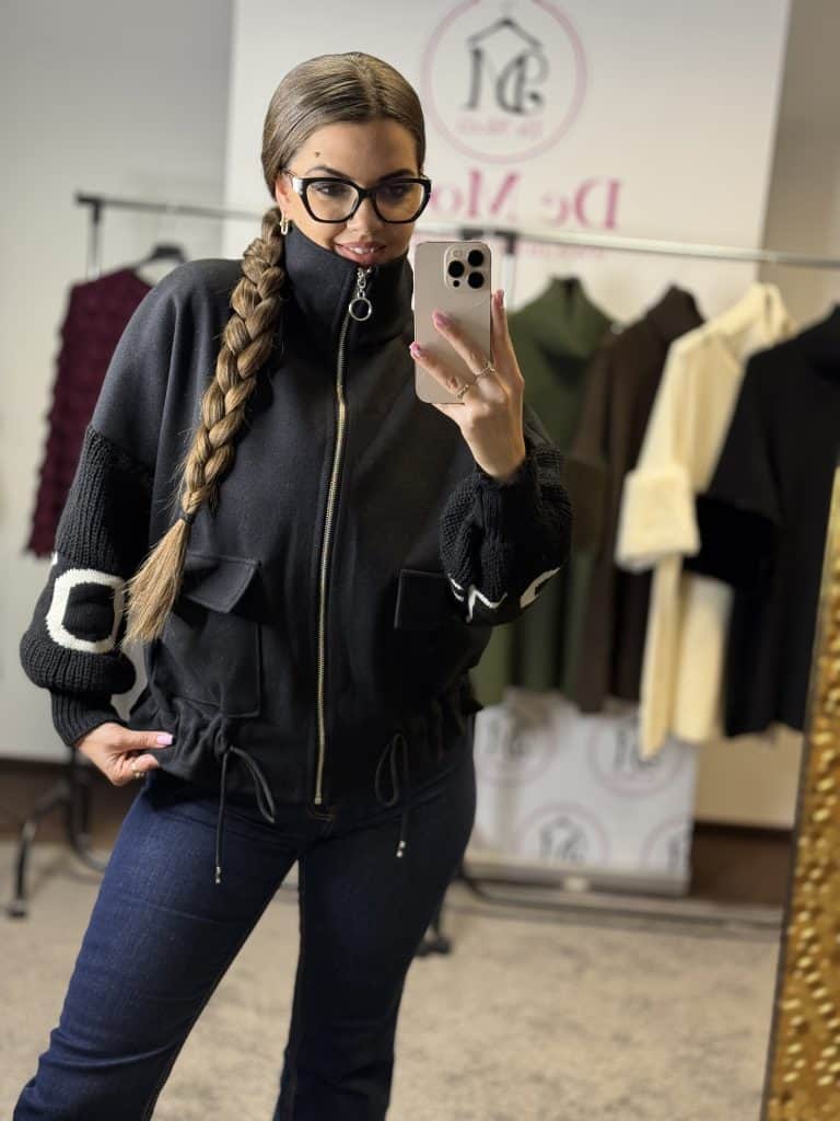 Női modell fekete kötött kabátot visel, fényképez selfie-t.