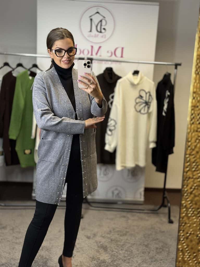 Női modell szürke kötött kardigánnal és fekete ruházattal.