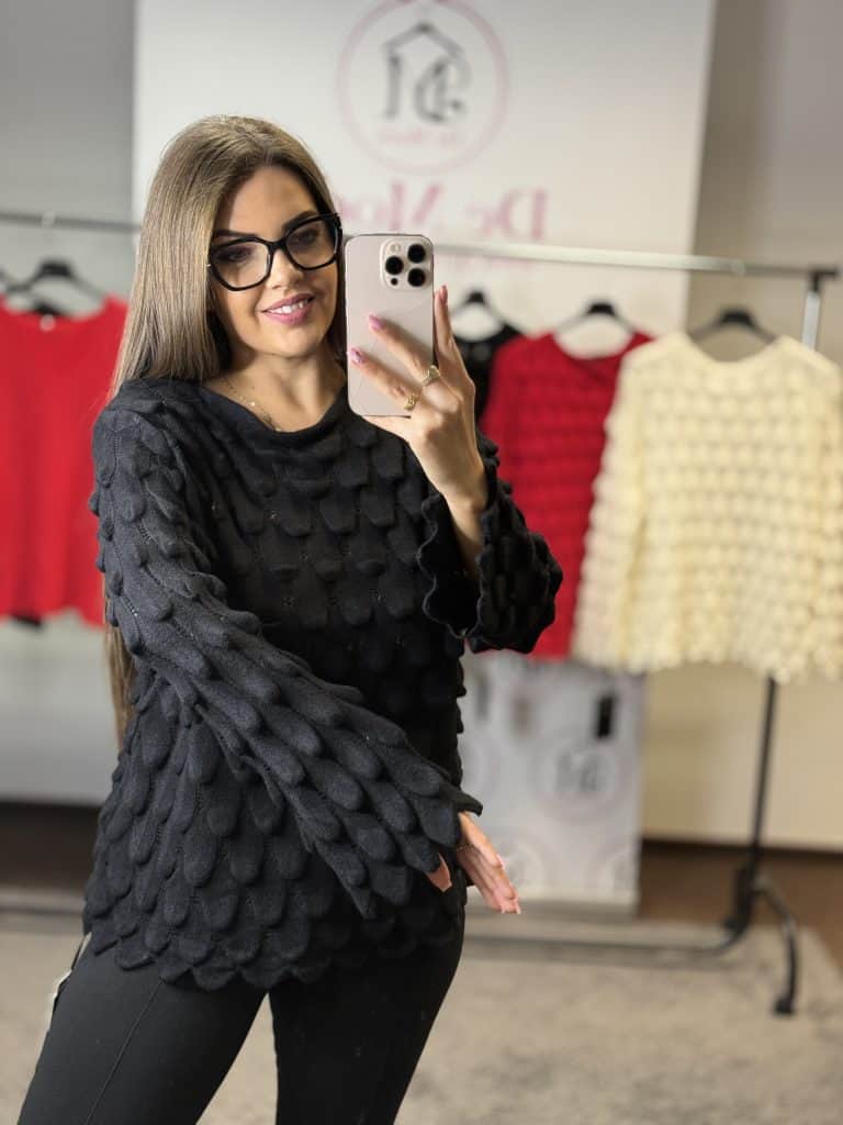 Női modell fekete kötött hosszított felsővel, szemüvegben, tükörkép selfie.