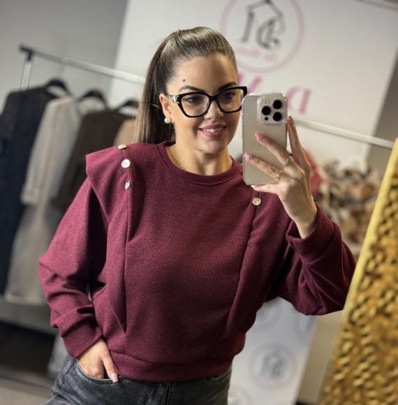 Vállánál fodros, arany színű gombokkal díszített,enyhén csillámos felső-bordó