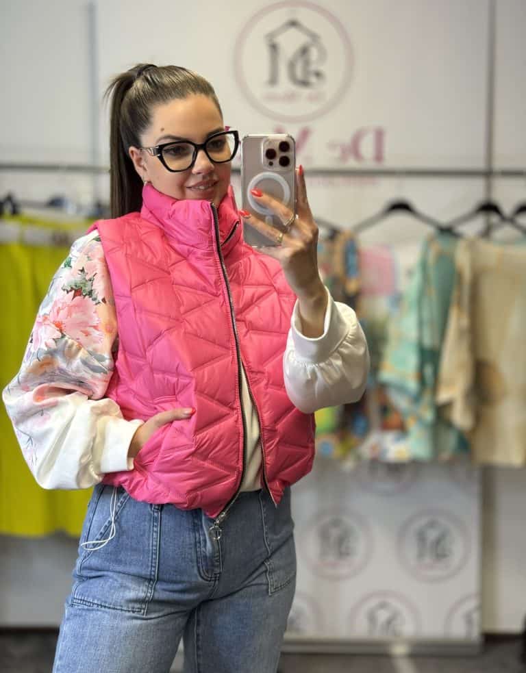 Női modell pink steppelt mellényben, szemüvegben, tükörkép selfie készítése.
