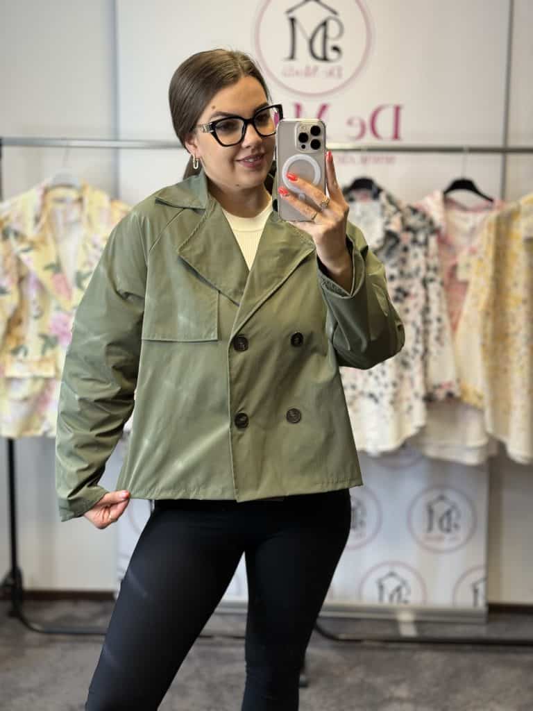 Női modell zöld oversize kabátban, tükörkép a ruhaboltban.