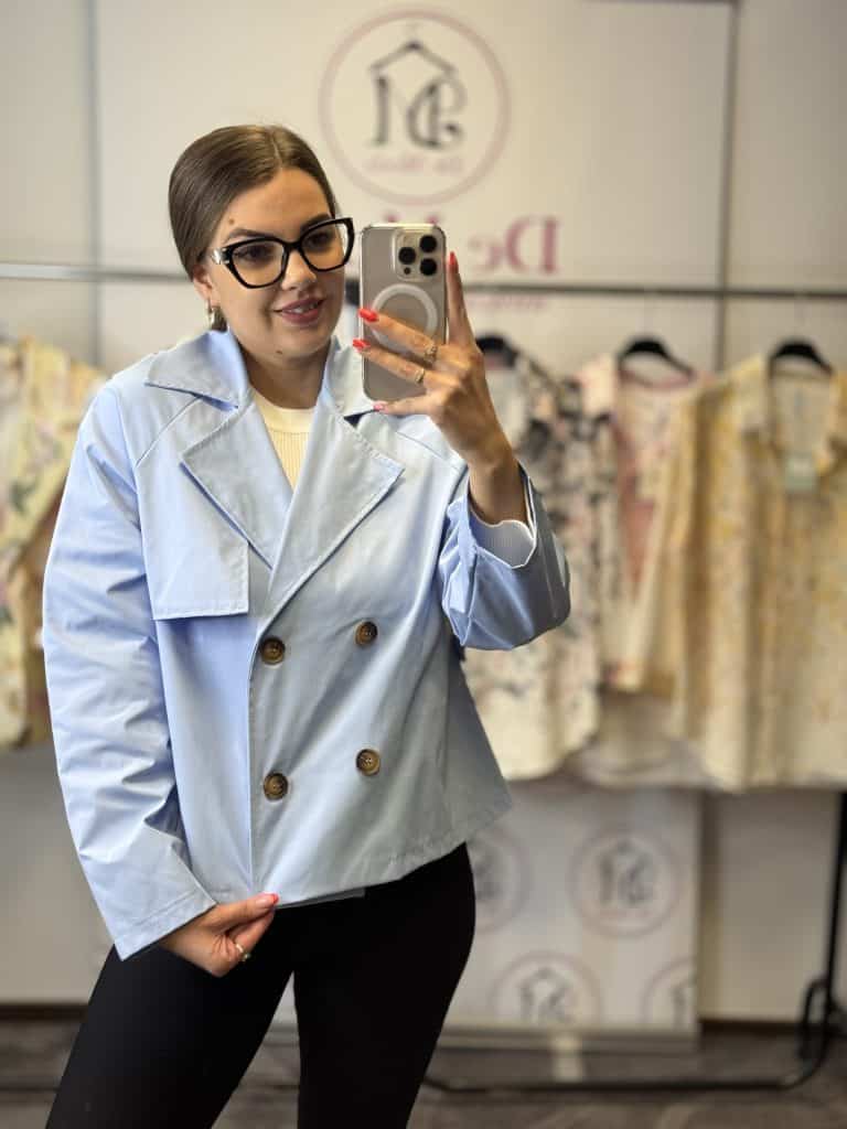 Női modell egy világoskék ballonkabátban, fényképez selfie-t.