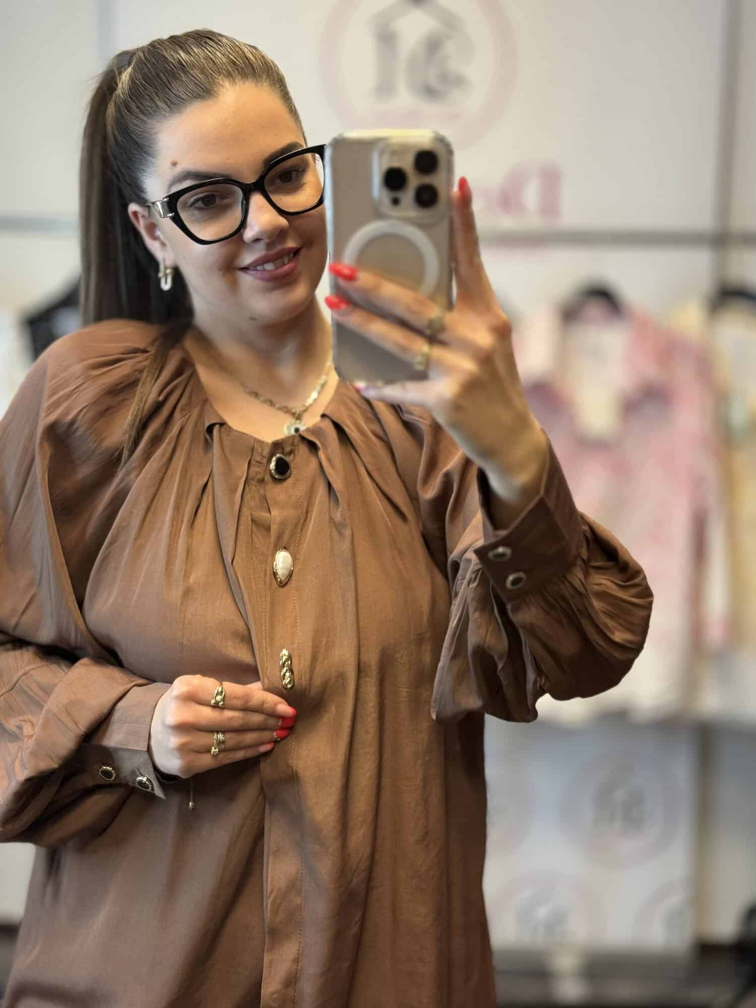 Női modell egy barna ingben, szemüvegben, selfie-t készít.
