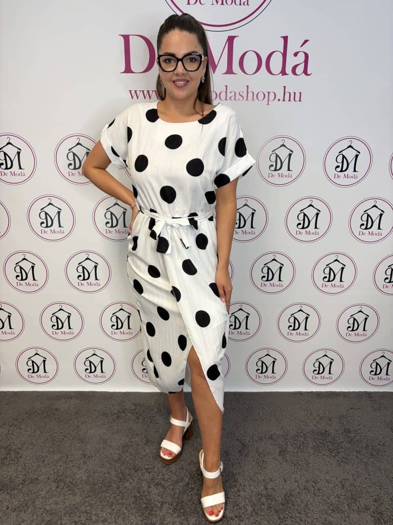 Női modell polka dot mintás fehér ruha, deréknál kötővel.
