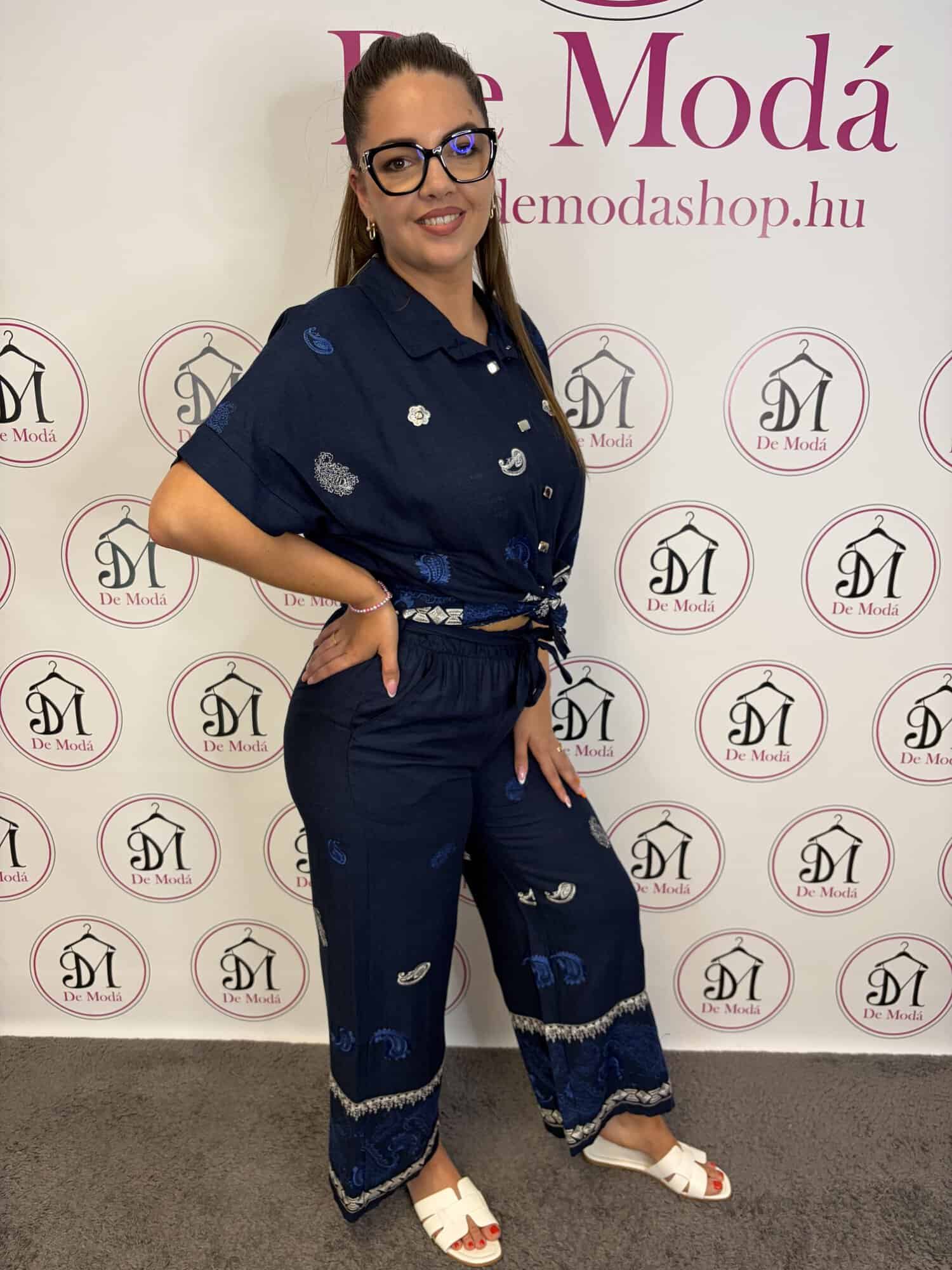 Női modell sötétkék nyári szett, nadrág és felső, modell állva, háttérben a De Moda logó.