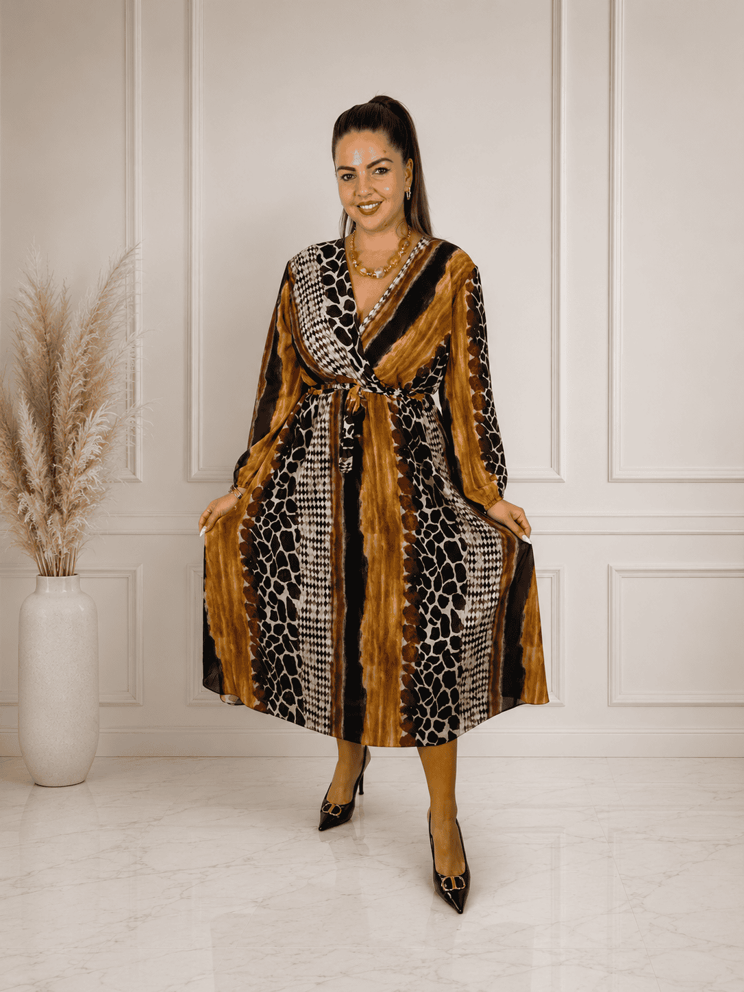 Női modell safari mintás maxi ruhában, magas sarkúval, elegáns környezetben.